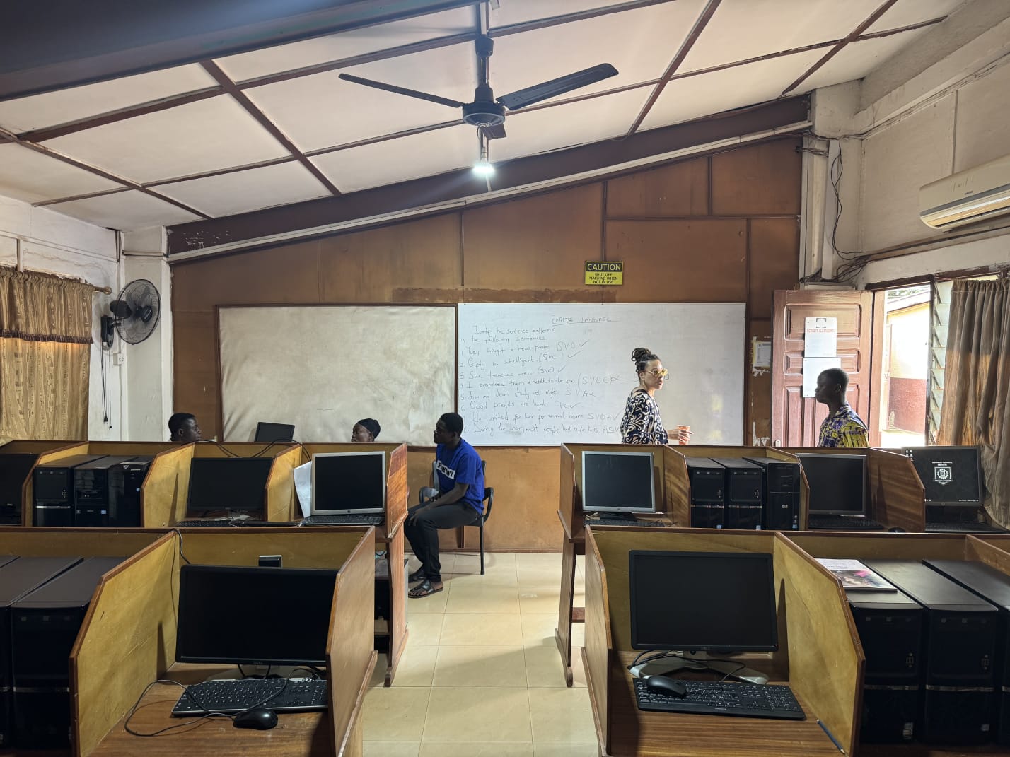 Teacher leading an English lesson in an ICT lab with computer workstations
