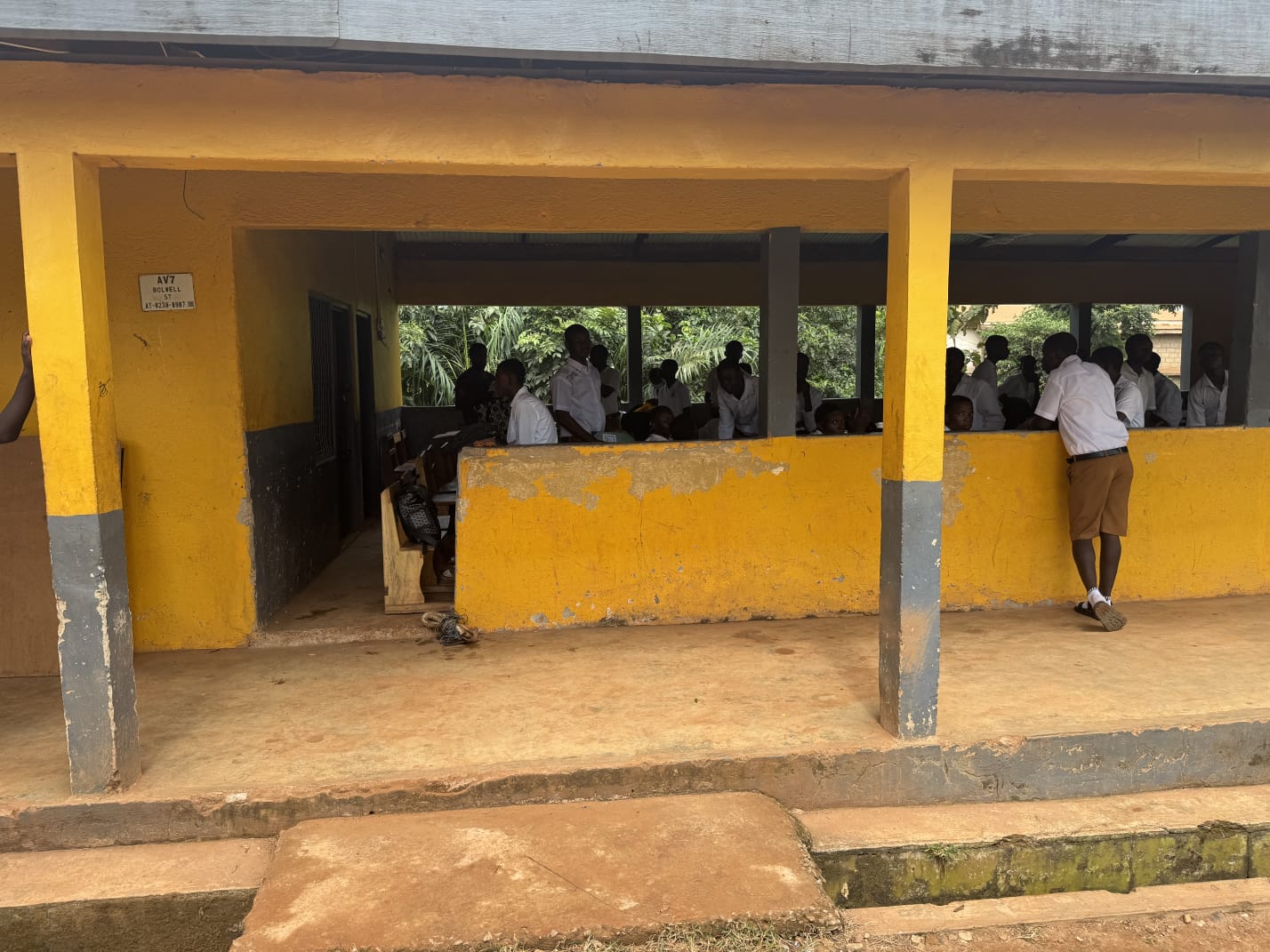 Students gathered in a yellow-painted open classroom block seen from the veranda