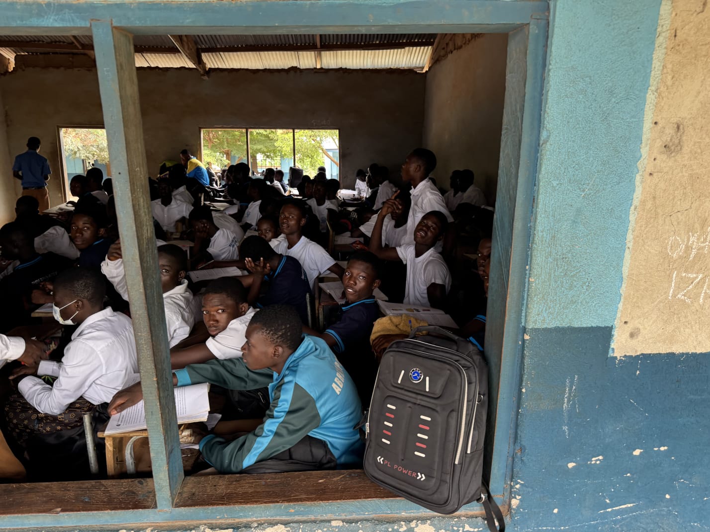 Students at desks with workbooks seen through a classroom window