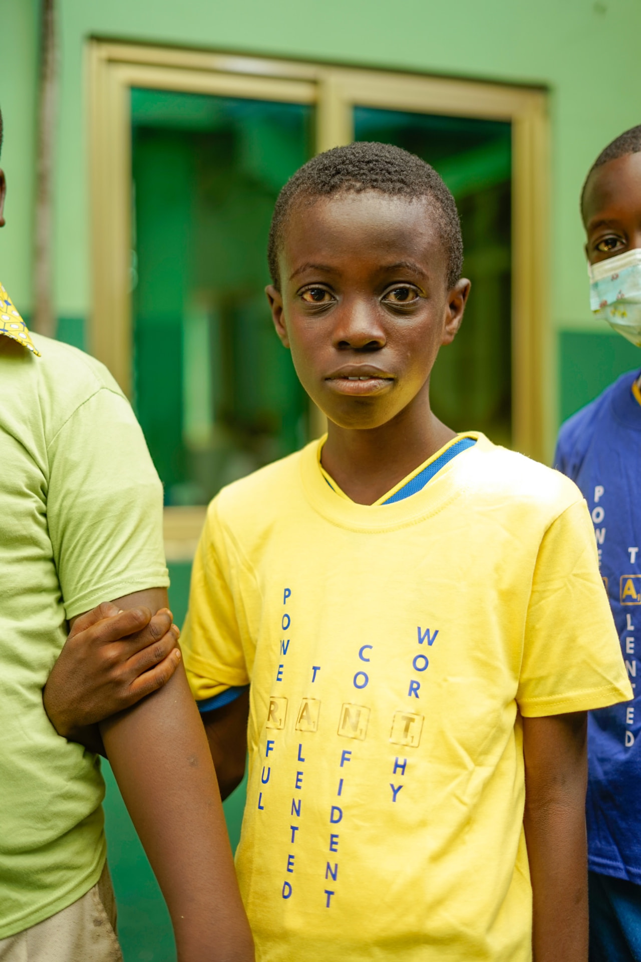 A learner in a yellow RANT t-shirt standing with classmates