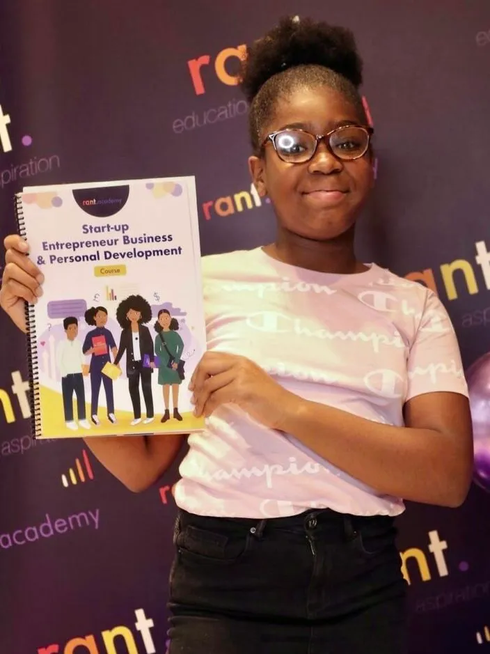 A learner holding the RANT Academy Start-up Entrepreneur Business and Personal Development course book in London